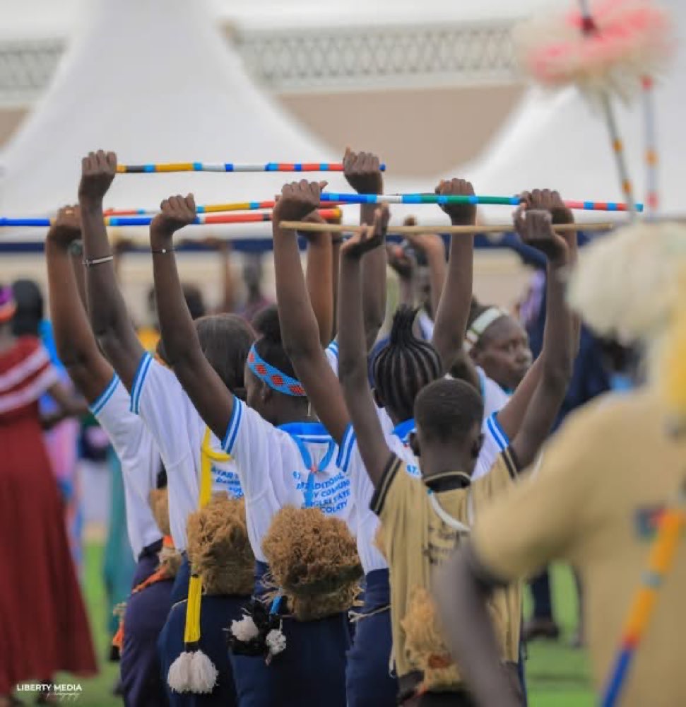 Young performers raise decorated sticks in unison during a performance